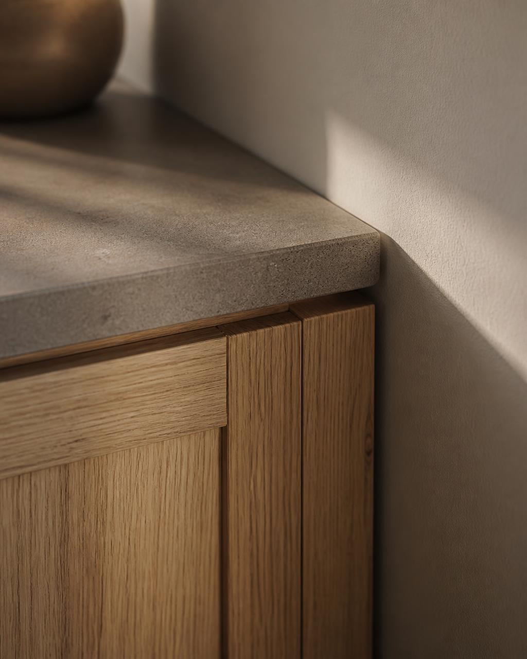 Unlacquered oak cabinet edge meeting a honed stone countertop in raking light